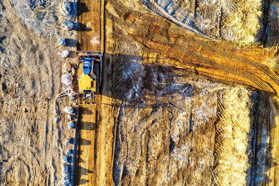 Top-down view of a bulldozer moving sand and rocks at a construction site in Rochester, MN.